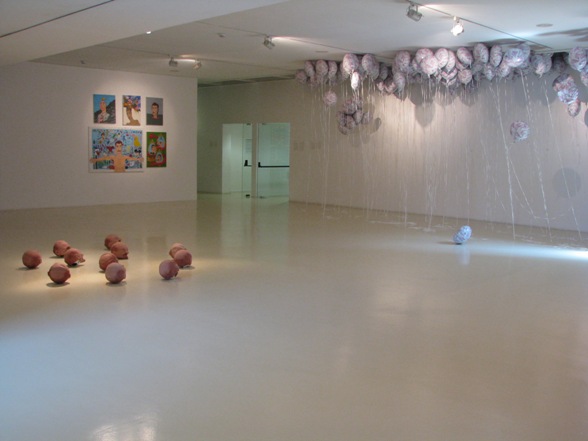 Partial gallery view of Parastou Forouhar's installation Thousandandone Day, 2003, digital print, balloons; Kendell Geers, Lenin Kicking against the Pricks, 2013, 11 soccer balls and latex masks